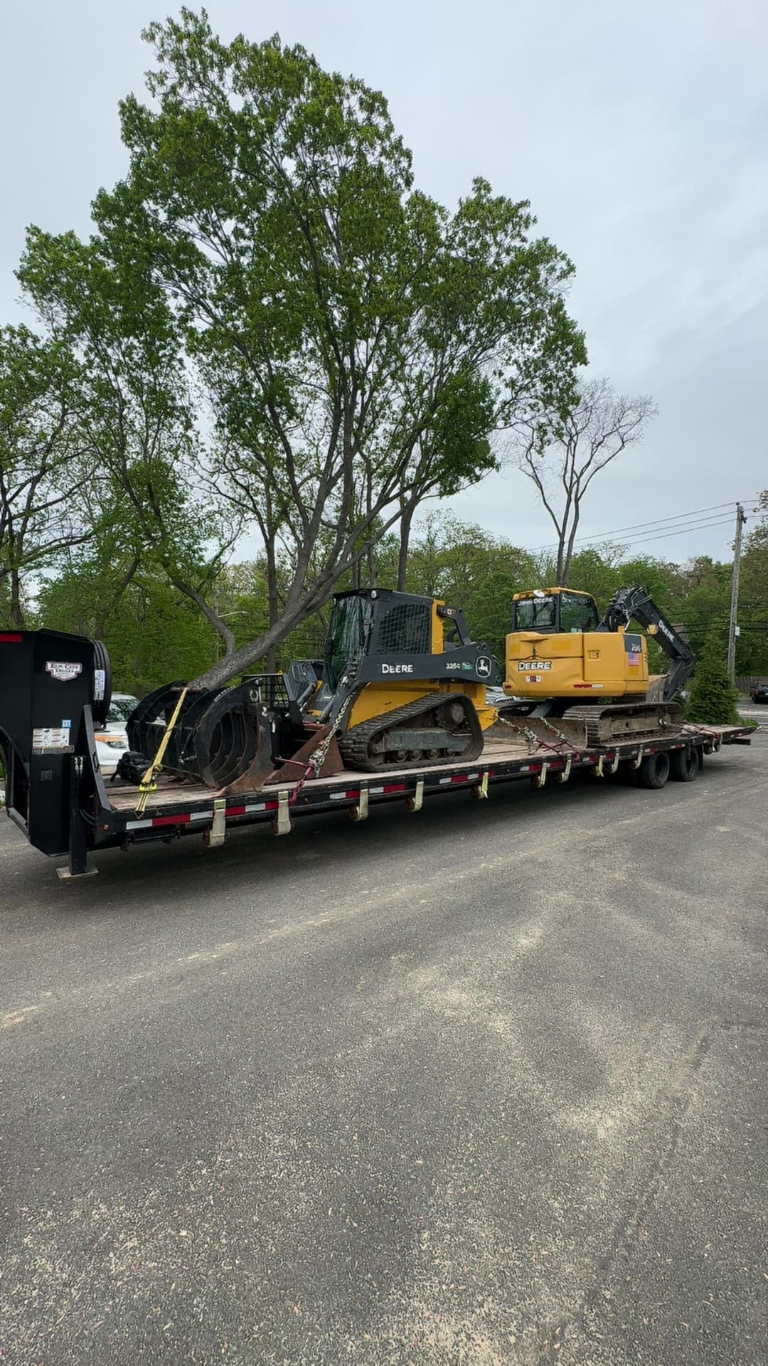 Heavy machinery on a flatbed trailer, including a Deere bulldozer and a Caterpillar excavator.
