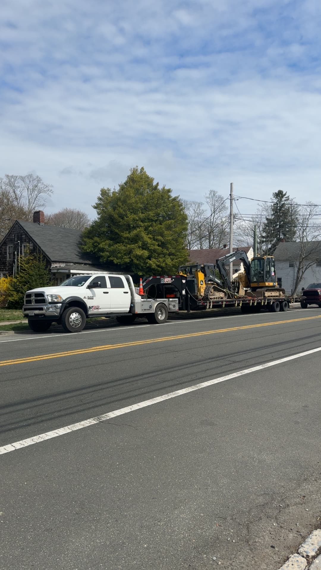 Construction truck with trailer carrying heavy machinery on a roadside.