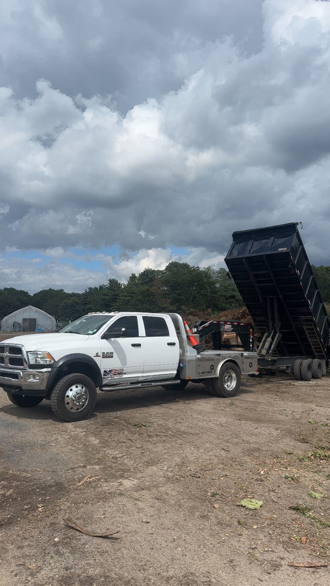White dump truck unloading materials under a cloudy sky. Ideal for construction or landscaping use.