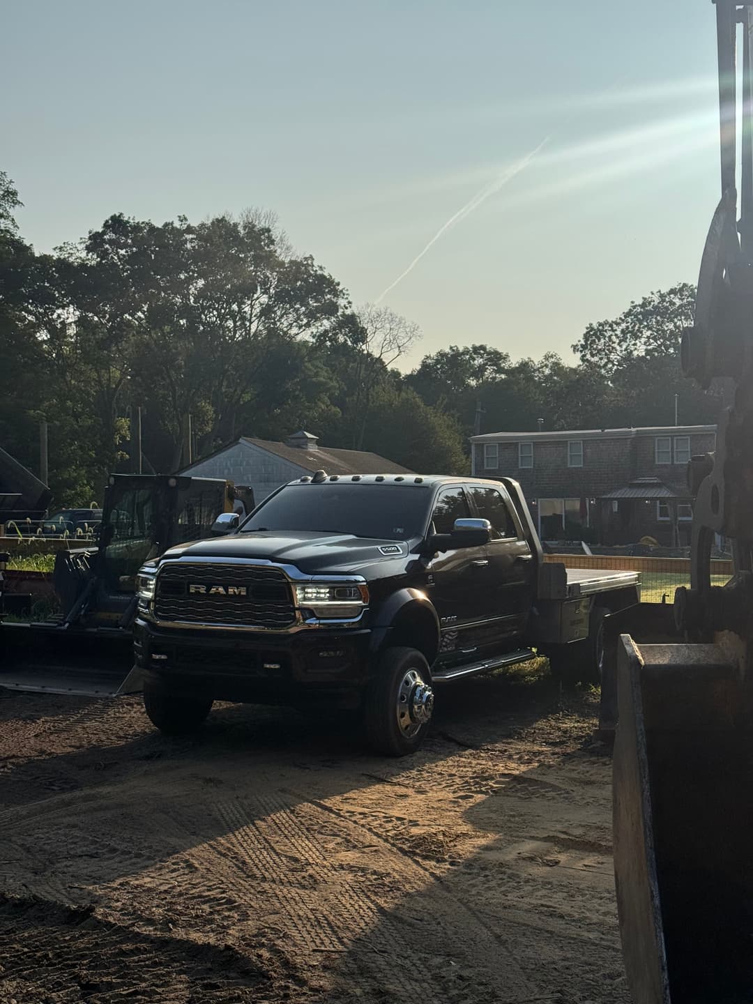 Black RAM truck parked on construction site with machinery in background and sunlight.