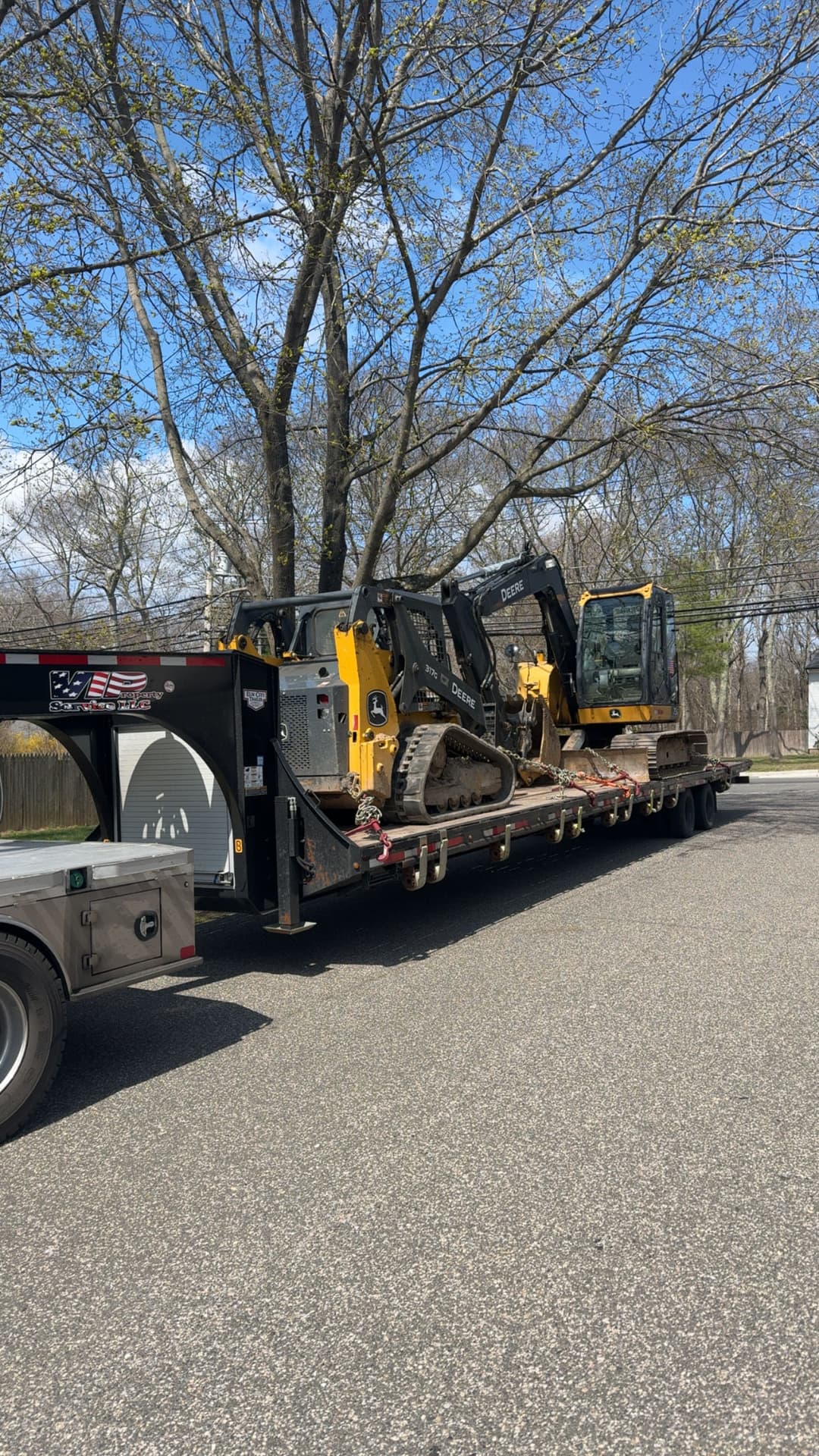 Heavy machinery on a flatbed truck, featuring two yellow excavators under a blue sky.
