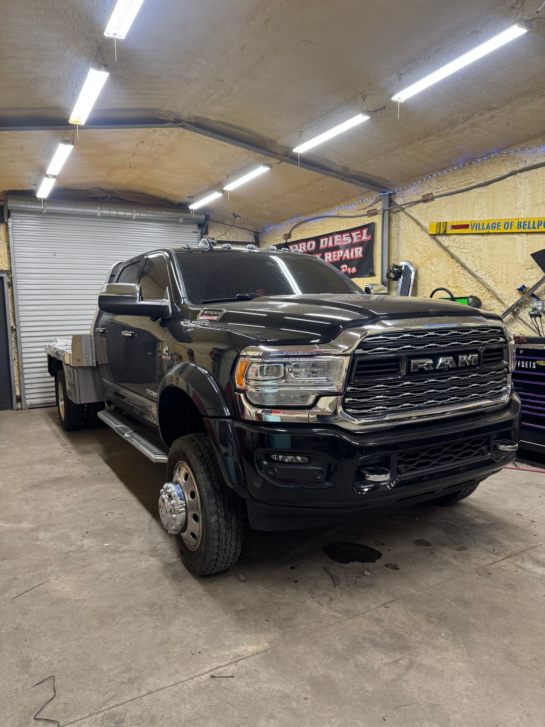 Black RAM truck with a flatbed in a well-lit garage setting. Ideal for heavy-duty work.