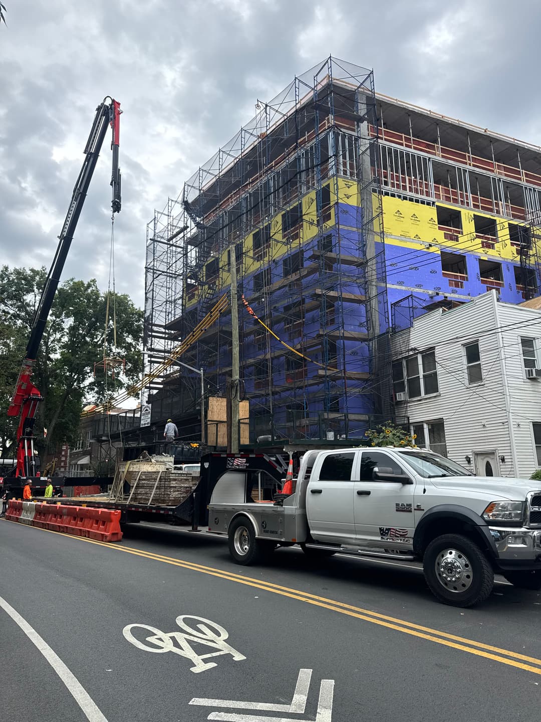 Construction site with crane and truck delivering materials to a multi-story building.