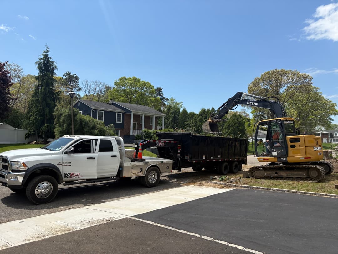 Excavator loading debris into a dump trailer during home construction project.