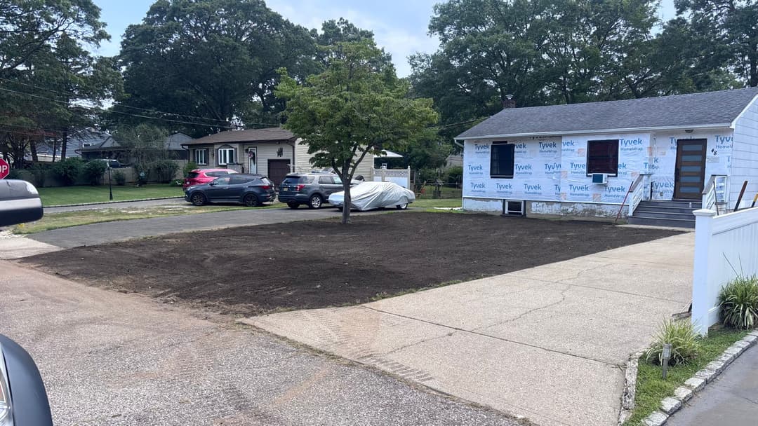 Residential property featuring a newly cleared yard, parked cars, and renovation work in progress.