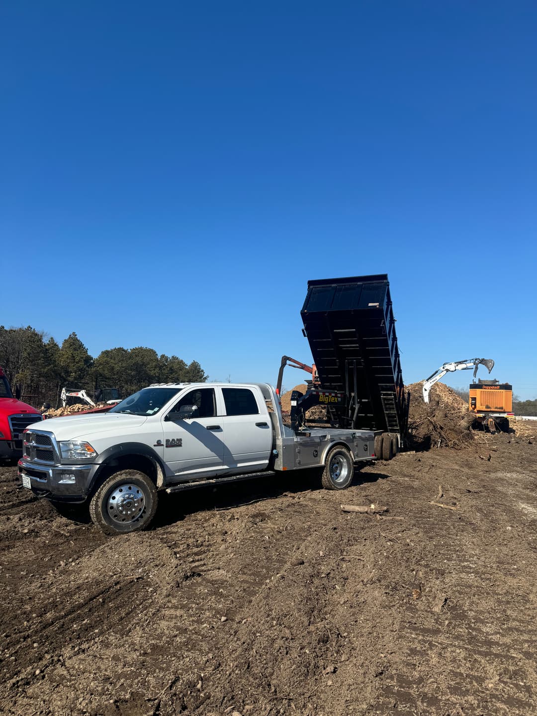 Dump truck unloading debris at a construction site under a clear blue sky.