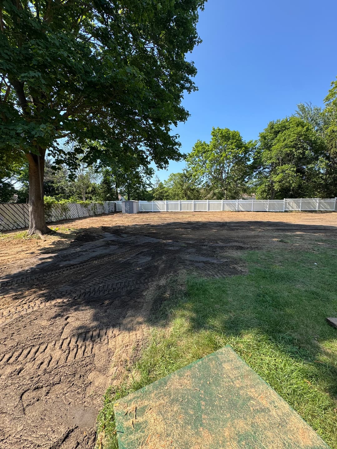 Cleared outdoor space surrounded by trees and a fence, ready for construction or landscaping.