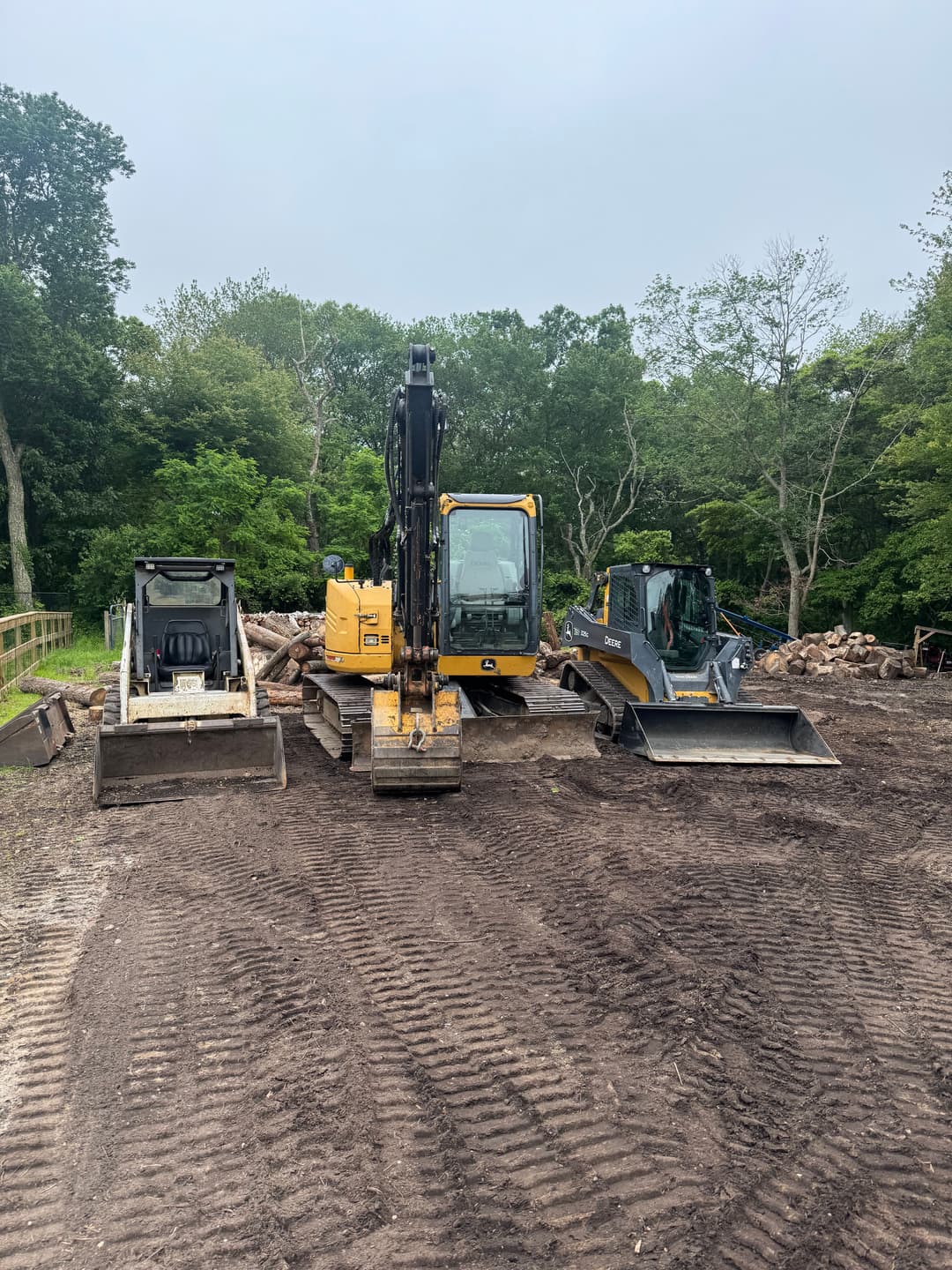 Construction site featuring three heavy machinery vehicles: an excavator and two bulldozers.
