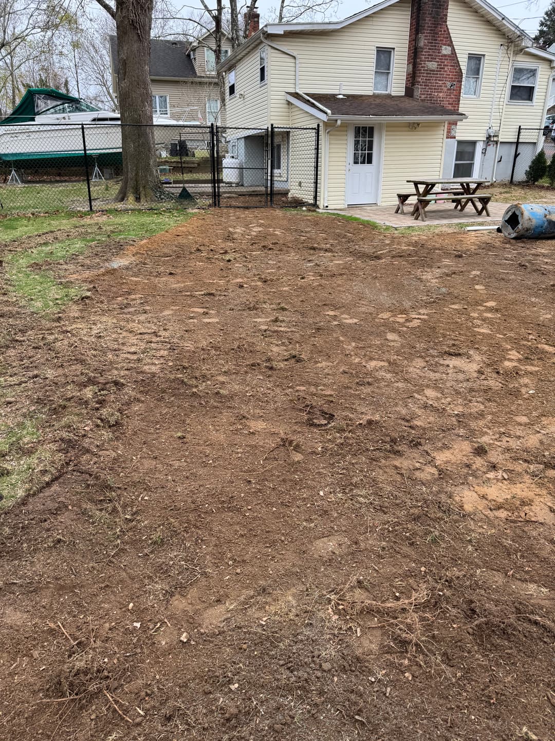 Cleared backyard area with dirt, house in background, ready for landscaping or construction.
